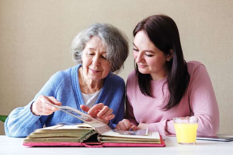 daughter and senior mom looking at a photo album