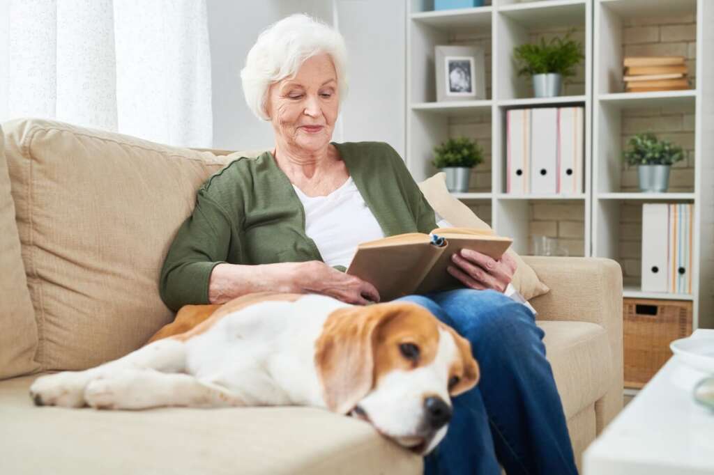 older adult with her dog reading a book