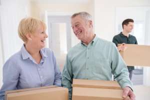 how to downsize for independent living two older adults holding packing boxes