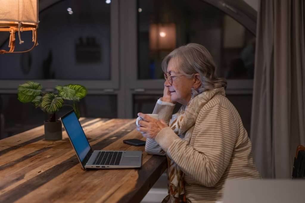 senior women sitting at kitchen table in the evening during daylight saving time and elderly parent